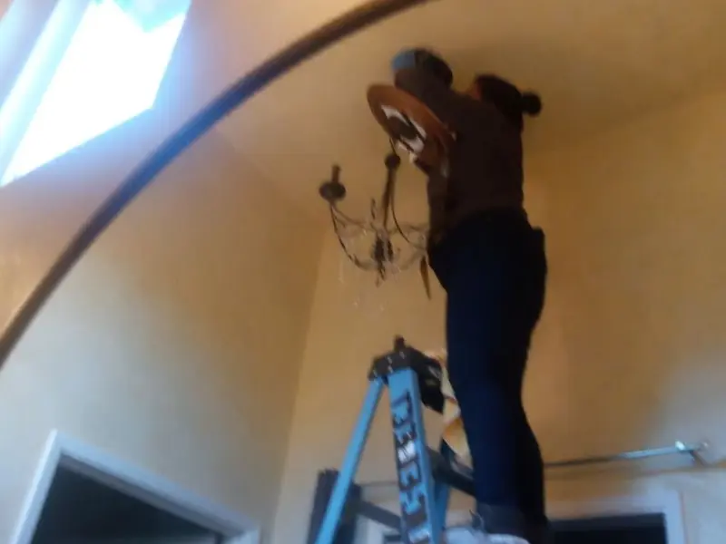 Electrician installing a chandelier in a Hollister residence